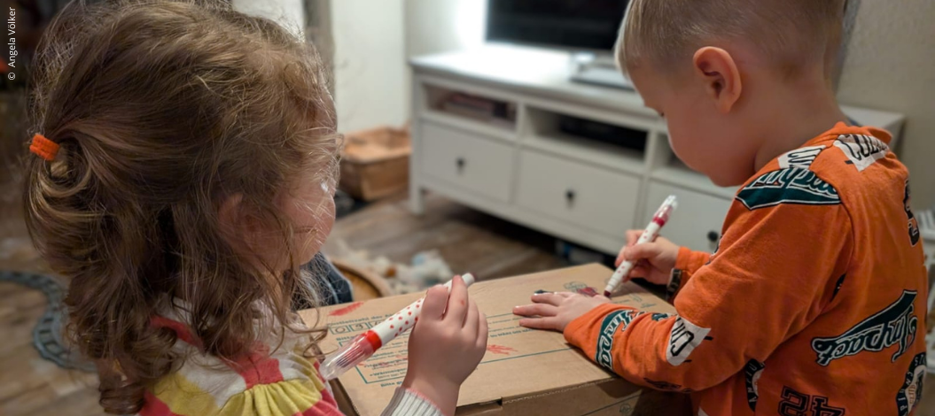 Anni (2 Jahre) und Emil (4 Jahre) verzieren das Paket, das Sie für die „Aktion Kinder helfen Kindern!“ gepackt haben. (Foto: Angela Völker)