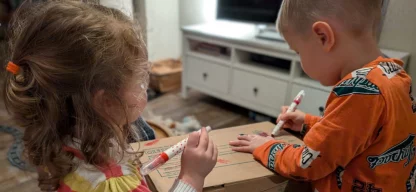 Anni (2 Jahre) und Emil (4 Jahre) verzieren das Paket, das Sie für die „Aktion Kinder helfen Kindern!“ gepackt haben. (Foto: Angela Völker)