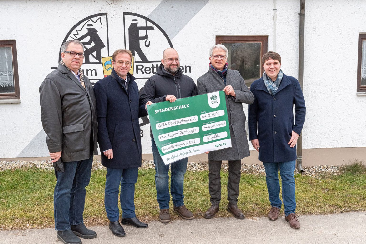 Christian Molke von ADRA Deutschland übergibt Spendenscheck über 20.000 Euro an Feuerwehrkommandant Timo Bablok, umringt von drei Kollegen.