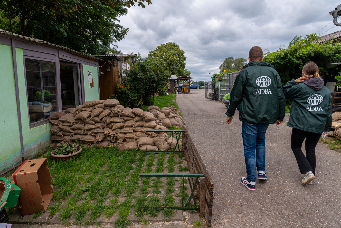 Zwei ADRA-Mitarbeitende gehen an einem Stapel Sandsäcke in Bayern vorbei.