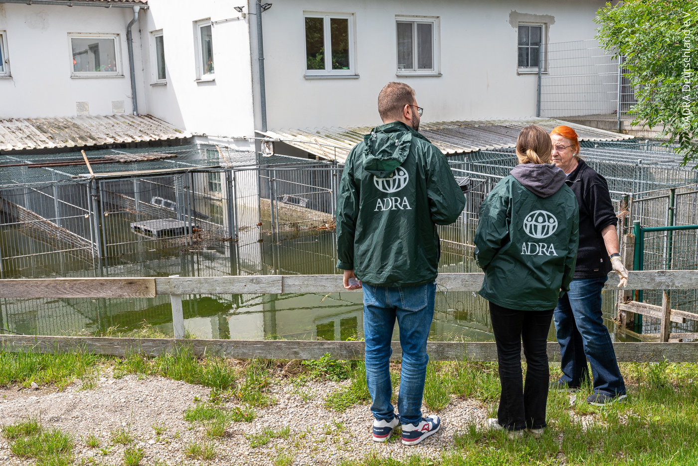 ADRA-Mitarbeitende sprechen mit einer Frau vor einem überfluteten Tierheim in Deutschland.