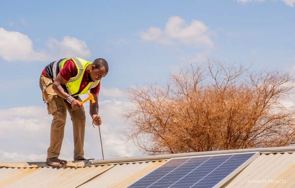 Ein Arbeiter montiert ein Solarpanel auf einem Dach in Tansania – das Projekt fördert grüne Technologien, Klimaschutz und nachhaltige Entwicklung.