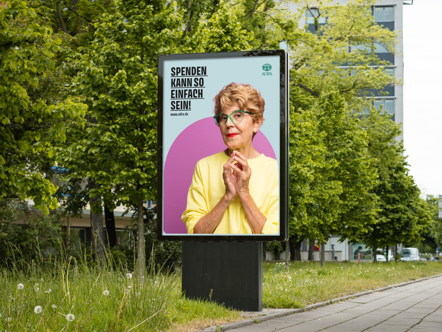 Großplakat mit älterer Frau in gelbem Pullover und Brille, Text „Spenden kann so einfach sein!“ – ADRA-Kampagne (Illustration: Peter Paul and Mary Werbeagentur GmbH & Co. KG)