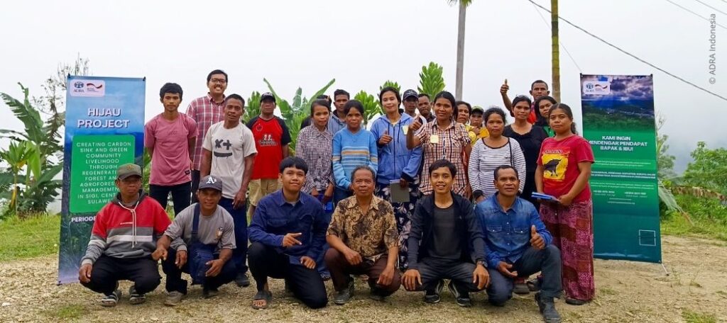 Gruppe indigener Dorfbewohner und Projektmitarbeiter bei einer Veranstaltung des ADRA-HIJAU-Projekts in Marawola Barat, Sigi, Indonesien, zur Förderung nachhaltiger Forstwirtschaft und Reduktion von CO2-Emissionen.