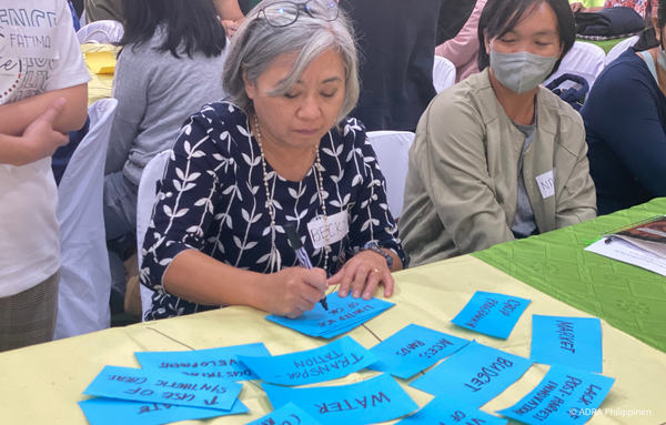 Eine Frau beschriftet blaue Karten während eines Workshops zur Katastrophenvorsorge im RISE-Projekt von ADRA in der Provinz Benguet, Philippinen.
