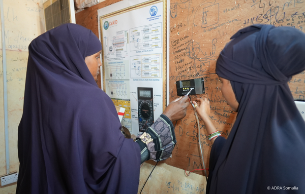 Zwei somalische Frauen lernen im Rahmen des ADRA-IMPACT-Projekts, wie ein Solarladeregler installiert wird – Teil der grünen Berufsbildung in Somalia.