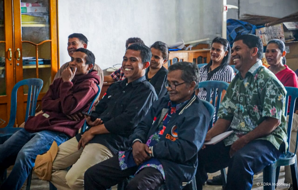 Teilnehmerinnen und Teilnehmer der Da’a-Gemeinschaft in Marawola Barat, Indonesien, lachen und hören aufmerksam während einer ADRA-Schulung zu nachhaltiger Entwicklung und Waldschutz.