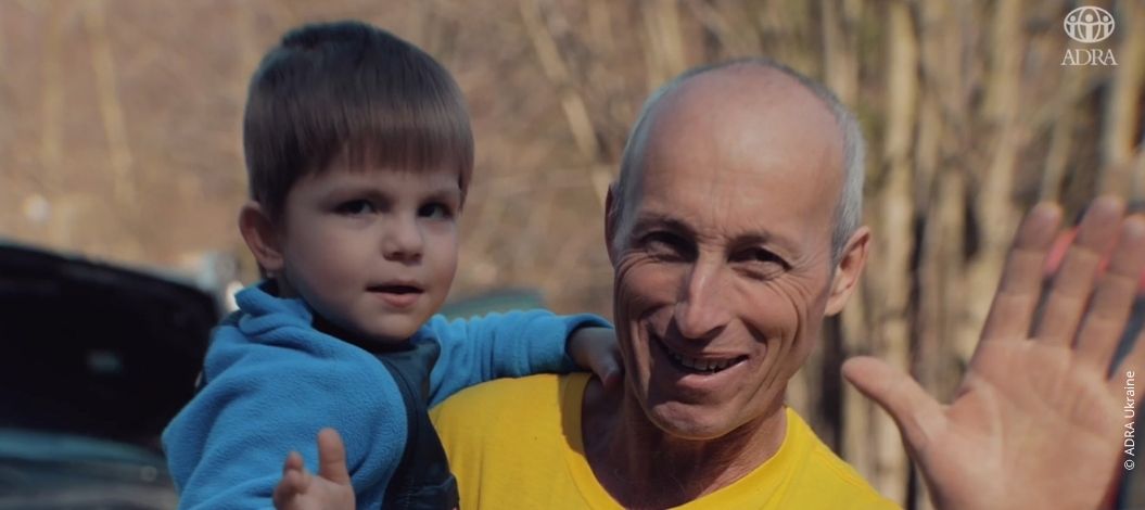 Ein ukrainischer Vater hält seinen Sohn Solomon auf dem Arm – beide lächeln dankbar in die Kamera. ADRA hat ihnen geholfen, dem Krieg zu entkommen.