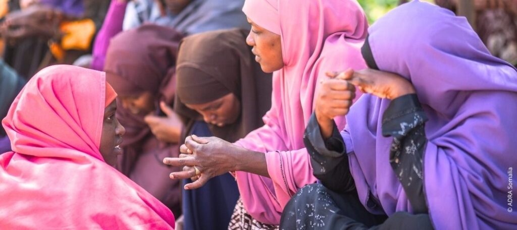Somalische Frauen in bunten Hijabs diskutieren während eines ADRA-Schulungsprojekts zur wirtschaftlichen Stärkung von Unternehmerinnen, das Frauen wirtschaftlich in Somalia stärken soll.