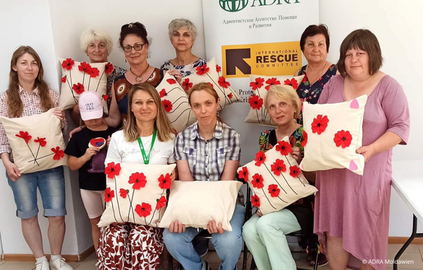 Frauen präsentieren selbstgenähte Kissen mit roten Blumen in einem ADRA-Projekt in Moldawien