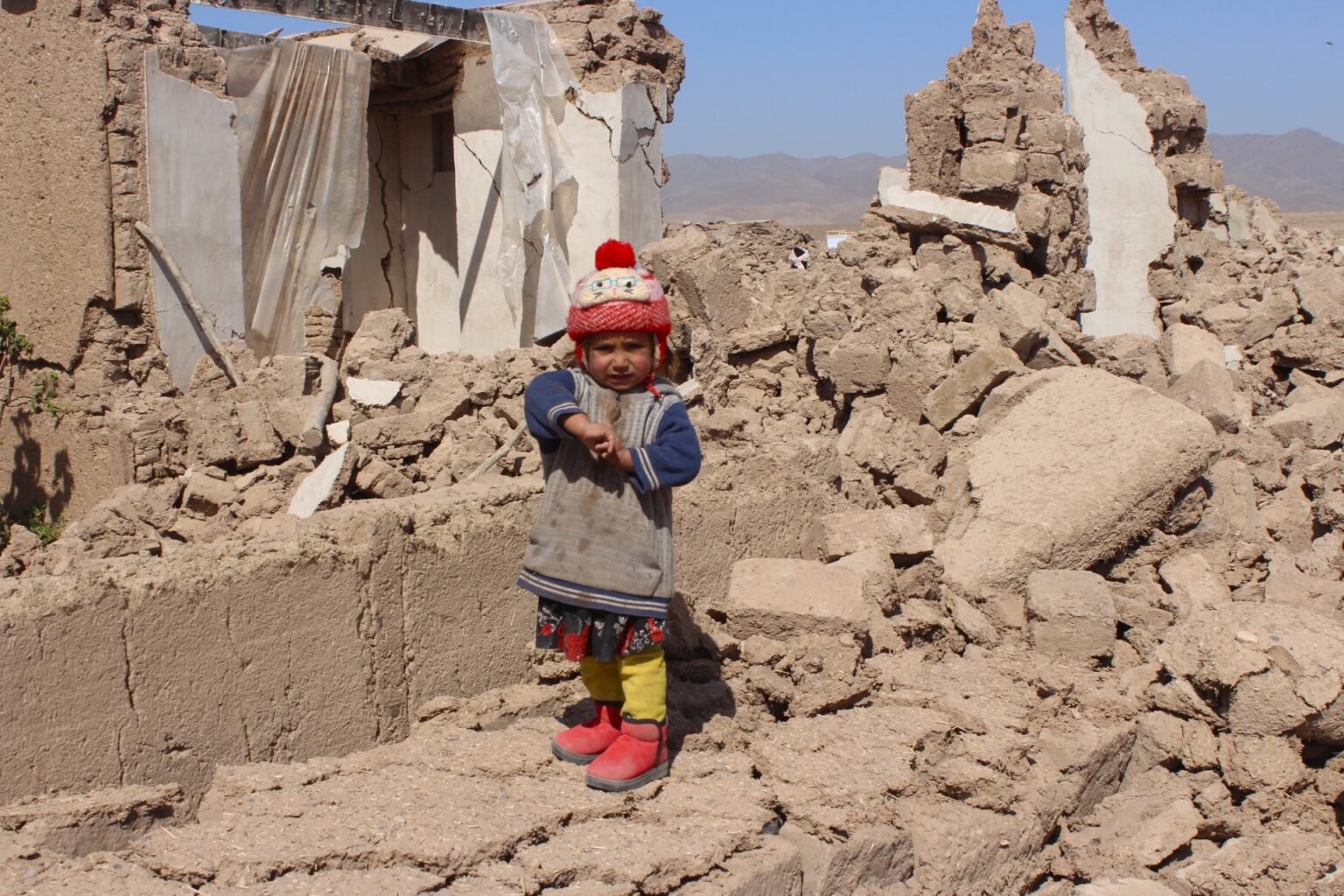 Kleines Kind steht in den Trümmern eines eingestürzten Hauses nach dem Erdbeben in Afghanistan, Symbolfoto für die Katastrophe
