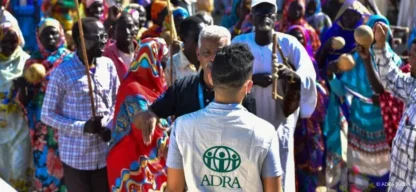 Mitarbeiter von ADRA im Gespräch mit einer Gruppe von Menschen in traditioneller Kleidung im Sudan.