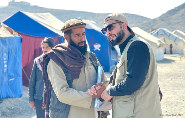 ADRA-Helfer spricht mit einem betroffenen Mann in einem Erdbeben-Nothilfecamp in Afghanistan.