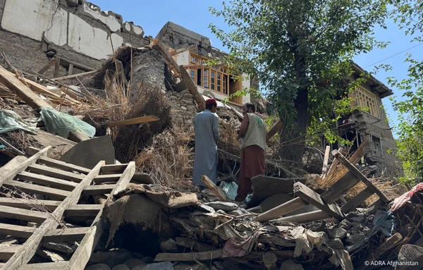 Zwei Männer stehen vor den Trümmern eines eingestürzten Hauses nach dem Erdbeben 2025.