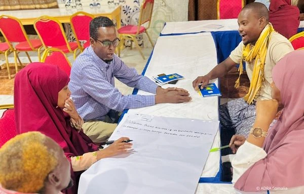 Mehrere Personen sitzen an einem Tisch und diskutieren in einer Arbeitsgruppe über ein großes Papier mit Notizen, im Rahmen eines Workshops zu Frühwarnsystemen und Katastrophenschutz.