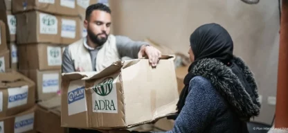 Hilfsgüterverteilung: Ein Helfer übergibt einer Frau ein ADRA-Paket in einem Lagerraum in Gaza.