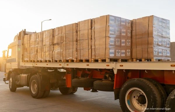 Ein LKW transportiert Hilfsgüter mit ADRA- und Plan-International-Logos für die humanitäre Hilfe im Gazastreifen.