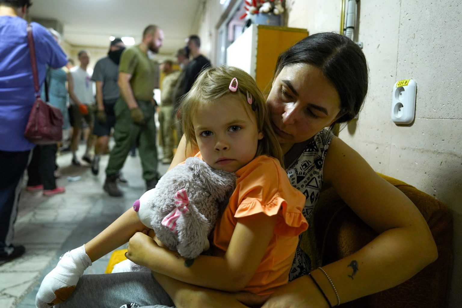 Eine Mutter sitzt mit ihrer kleinen Tochter auf dem Arm in einem Krankenhausflur in Kiew nach einem Raketenangriff.
