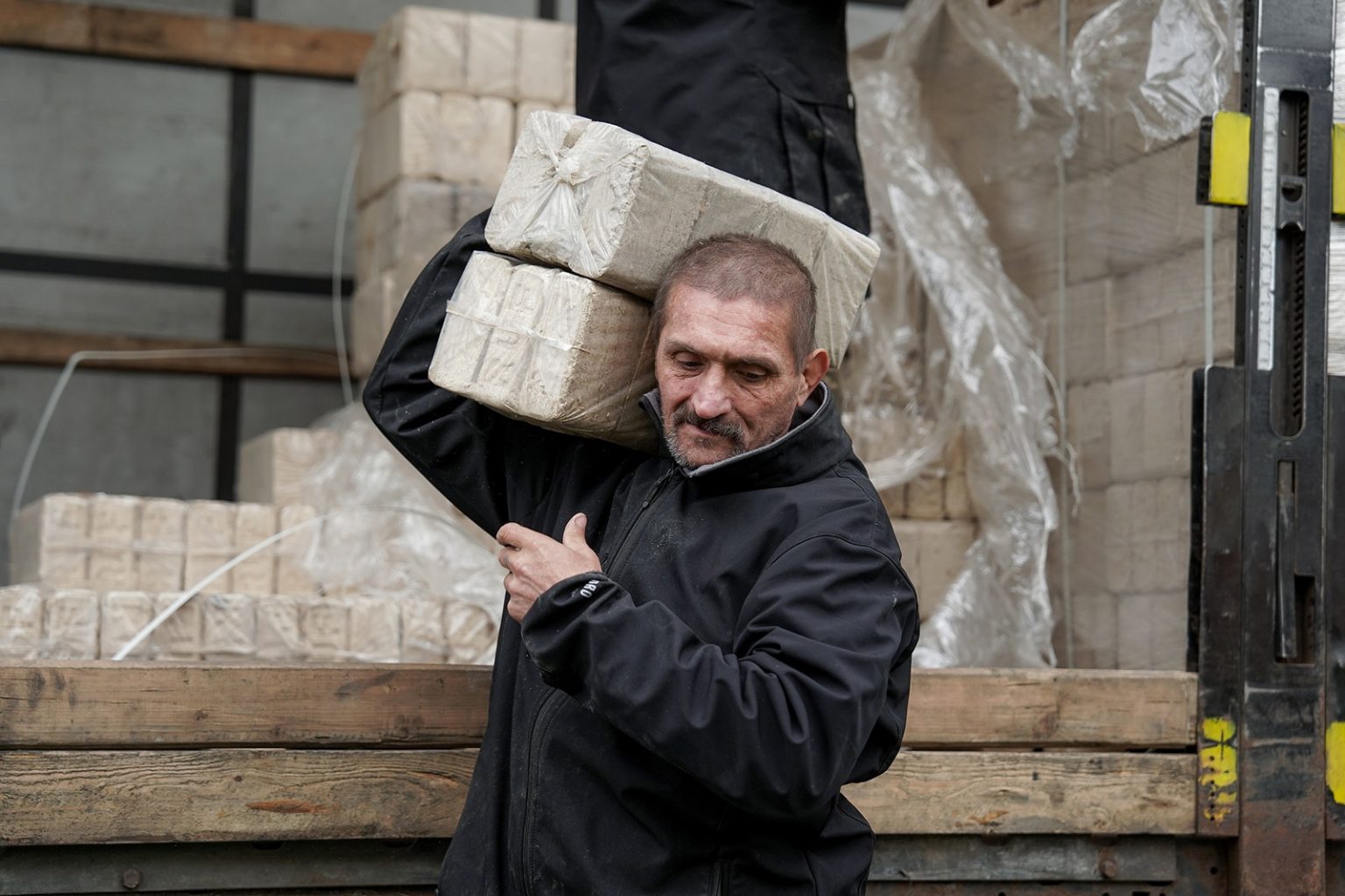 Ein Mann trägt gepresste Brennstoffblöcke von einem Lkw, die im Rahmen der ADRA-Winterhilfe in der Ukraine verteilt werden.