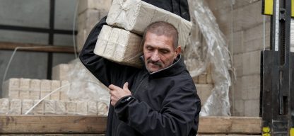 Ein Mann trägt gepresste Brennstoffblöcke von einem Lkw, die im Rahmen der ADRA-Winterhilfe in der Ukraine verteilt werden.