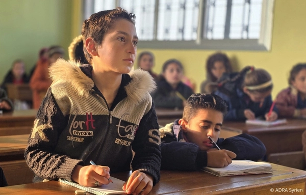 Schüler in einer von ADRA wiederhergestellten Schule in Syrien schreiben im Unterricht nach dem Erdbeben von 2023.