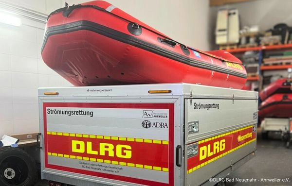 DLRG-Strömungsrettungsanhänger mit aufgeladenem Schlauchboot in einer Fahrzeughalle, eingesetzt für Hochwassereinsätze im Ahrtal.