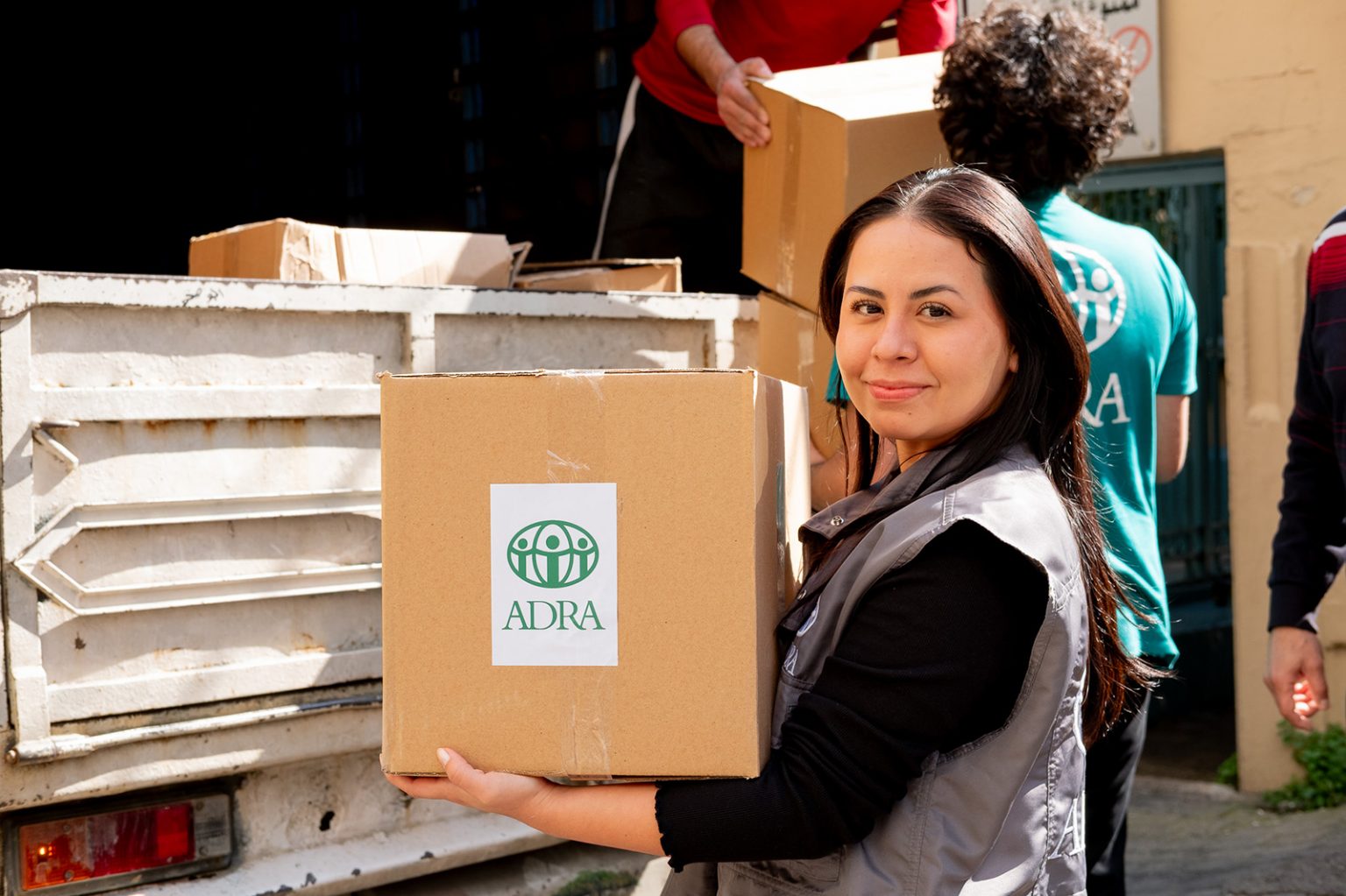 ADRA-Helferin trägt Karton mit Hilfsgütern während einer Verteilung an vertriebene Familien im Libanon.