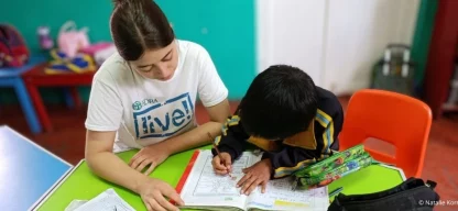 Junge ADRAlive!-Freiwillige unterstützt ein Schulkind beim Lernen in einem Klassenraum im Globalen Süden