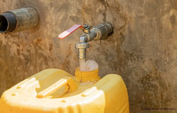 Wasser fließt aus einer Zapfstelle in einen gelben Wasserkanister in einem Dorf der Demokratischen Republik Kongo.