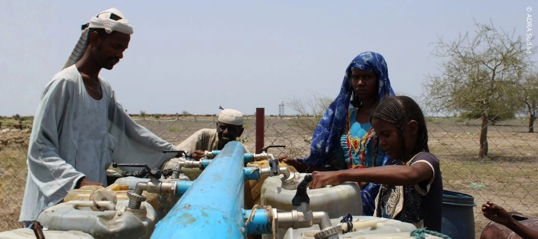 Eine Familie im Sudan füllt Wasserkanister an einer zentralen Wasserstelle auf.