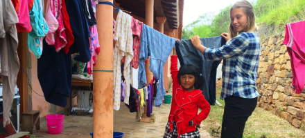 ADRAlive! Freiwillige Diana und ein hilfsbereites Mädchen hängen Wäsche zum Trocknen auf eine Wäscheleine in Bolivien