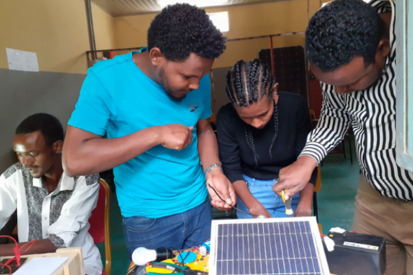 Drei Jugendliche bauen eine Solaranlage während eines Trainings im Bereich PV-Solarenergie