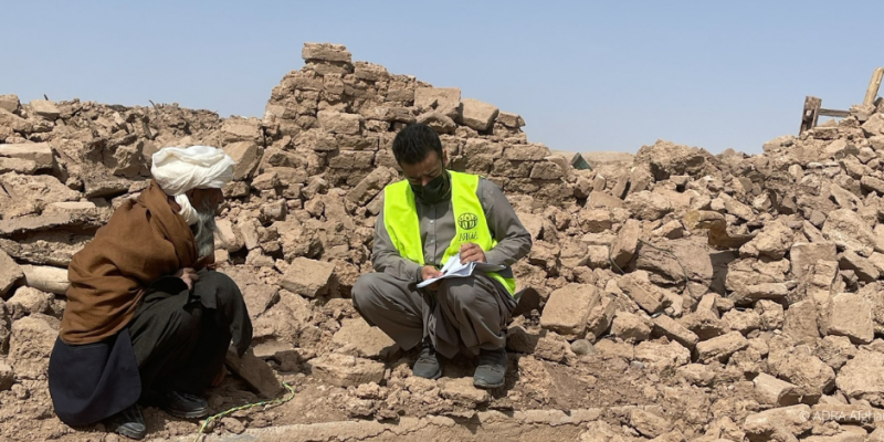 Nach dem verheerenden Erdbeben in Herat: Ein ADRA-Mitarbeiter sitzt einfühlsam mit einem betroffenen Mann auf den Trümmern, zeigt Mitgefühl und steht bereit, Unterstützung in der akuten Notlage Afghanistans zu bieten.
