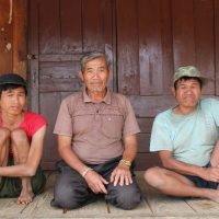 Drei Männer sitzen auf dem Boden und schauen in die Kamera