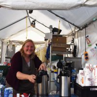 Eine lächelnde Mitarbeiterin des Cafés Ahrche befüllt Kaffee aus einer Kaffeekanne in eine Tasse unter einem Pavillon nach den Ereignissen der Flutkatastrophe