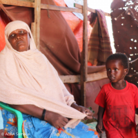 Mutter sitzt mit ihrem Kind in einer Behausung