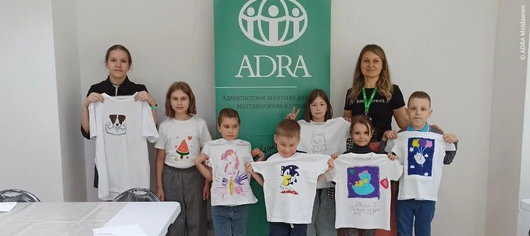 Kinder zeigen stolz bemalte T-Shirts in einem ADRA-Integrationsworkshop in Moldawien