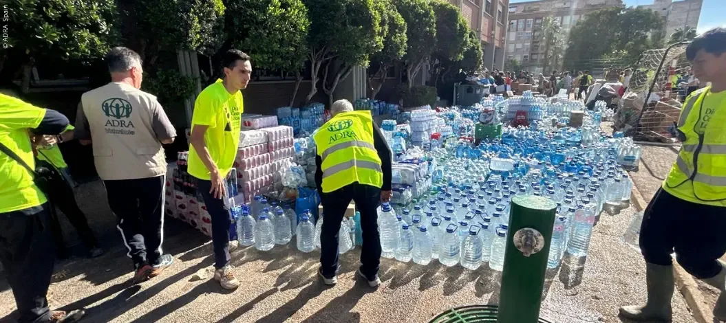 Header_ADRA_Valencia Tödliche Überschwemmungen in Spanien - Hunderte Wasserflaschen und Hilfsgüter werden vor einem Schulgebäude gestapelt.