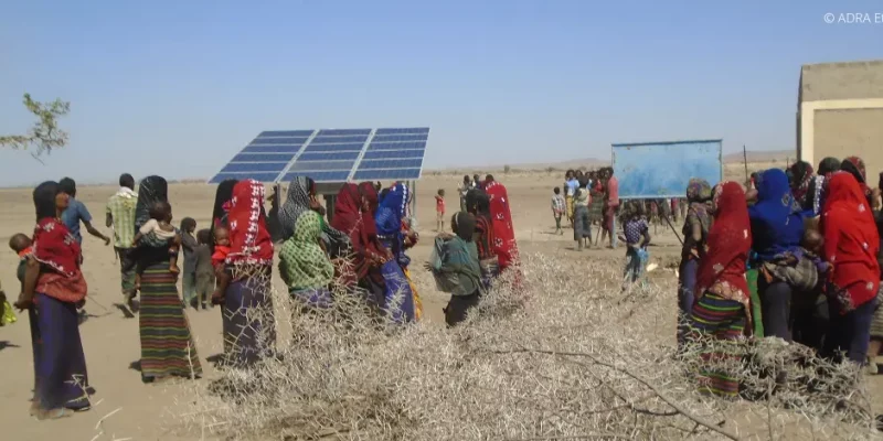 Eine Gruppe von Einwohnern in Äthiopien steht im Freien und bewundert die fertiggebaute Solaranlage.