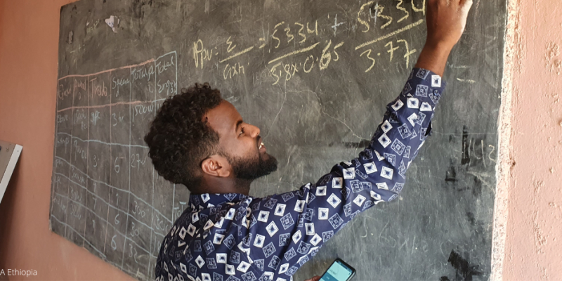 Ein jugendlicher in Äthiopien rechnet eine Matheaufgabe an einer Tafel in der Schule.