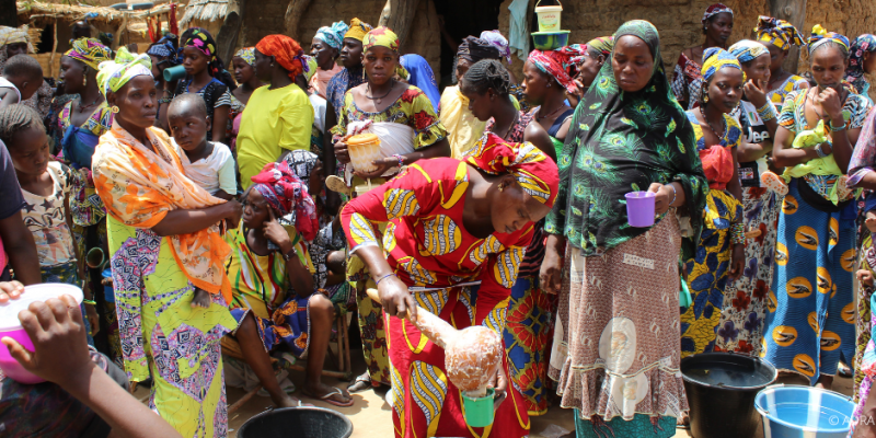 Frauen und Kinder in Togo kochen gemeinsam im Freien mit traditionellen Methoden