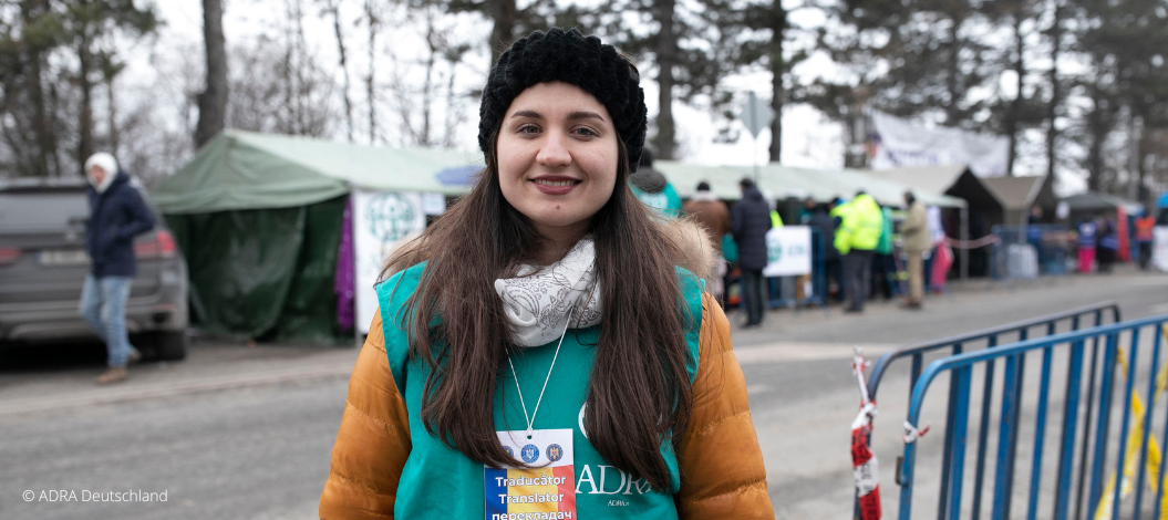 Eine ehrenamtliche Helferin der Landessammlung in einer grünen ADRA-Weste mitten auf einer Straße, auf der Zelte für Geflüchtete aufgebaut wurden