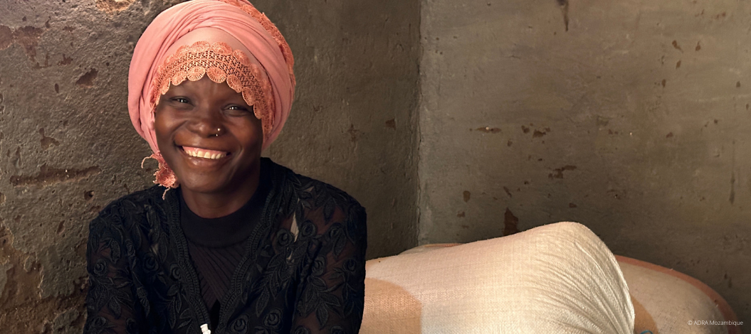 Lachende Frau mit Kopftuch in einfacher Behausung.