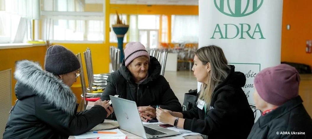ADRA Ukraine Mitarbeitende beraten ältere Menschen über Hilfsangebote und humanitäre Unterstützung in einer Notunterkunft.