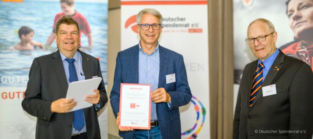 Christian Molke, Vorstandsvorsitzender von ADRA Deutschland e.V. (Mitte) nimmt die Urkunde mit dem Spendenzertifikat von Martin Wulff, Geschäftsführer (links) und Wolfgang Stückemann, Ehrenvorsitzender des Deutschen Spendenrates (rechts), entgegen. (Foto: Deutscher Spendenrat e.V.)