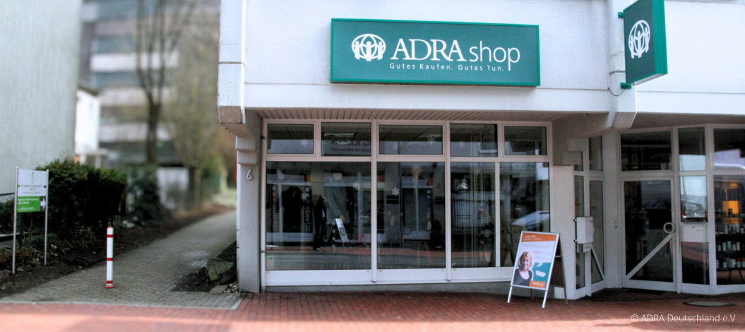 Außenansicht des ADRAshops in Lüdenscheid, der mit seinem einladenden Schaufenster auf die angebotenen Waren und sozialen Projekte aufmerksam macht