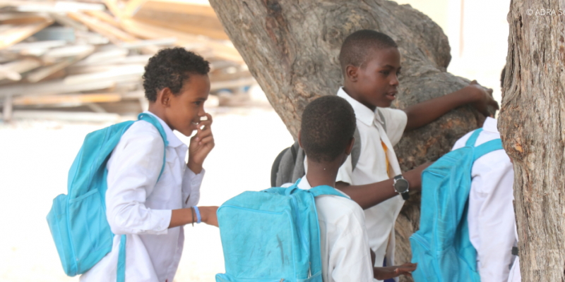 Vier junge Schüler in Somalia mit ihren hellblauen Rucksäcken, sind auf dem Weg zur Schule.