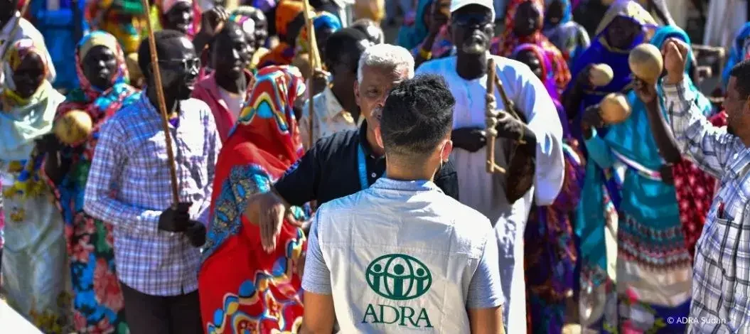 Mitarbeiter von ADRA im Gespräch mit einer Gruppe von Menschen in traditioneller Kleidung im Sudan.