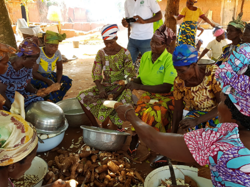 Eine Gruppe Frauen in togolesischer Kleidung sitzt auf dem Boden und bereitet Essen vor
