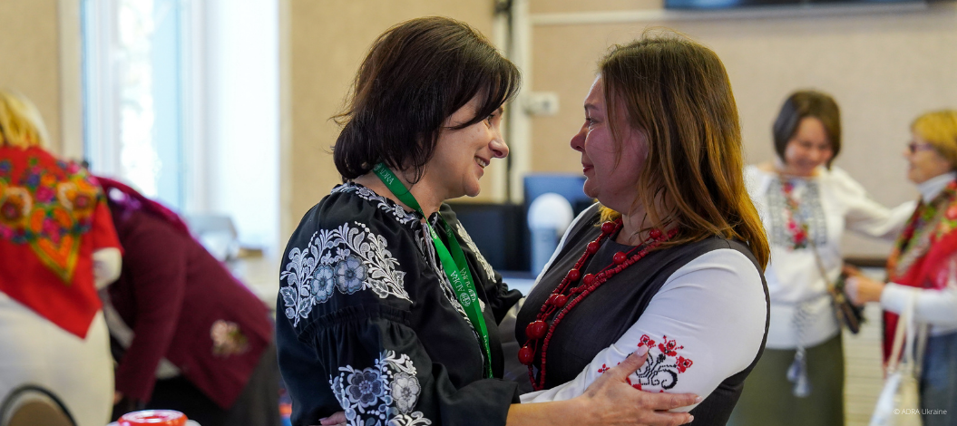 Zwei Frauen in traditioneller ukrainischer Kleidung umarmen sich.